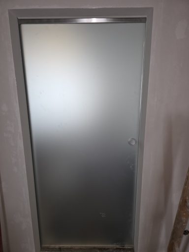 Glasschiebetür – Ansicht nach der Türblattmontage Geschlossene Glasschiebetür mit rundem Griff – Baustellenansicht